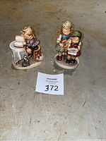 Photo of both Hummel figurines together on floor with auction tag