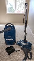 Kenmore Elegance vacuum cleaner with blue body, handle, hose, and Powermate Jr carpet cleaning attachment on carpeted floor.