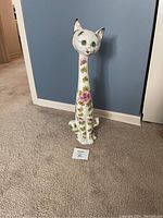 Front view of tall porcelain cat figurine showing detailed hand-painted floral design and face