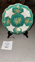 Porcelain plate displayed upright on a black plate stand, front view showing design and colors.