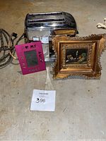 Photo showing vintage toaster, pink 'I heart my aunt' picture frame, and gold ornate picture frame with still life painting