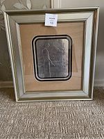 Full view of framed Effleurement aluminum embossed wall art by Emile Bellet showing the silver frame and tan matte.