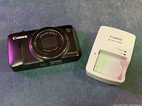 Front view of camera and charger on table showing charger beside camera