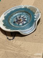 Top side view showing blue, green, and white glazed ceramic candle plate with wavy edges and abstract pattern.