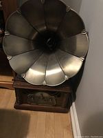 Photo showing the large metal gramophone horn speaker and wooden base unit with stereo controls.
