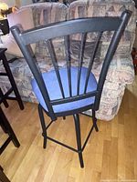 Side view of the bar chair showing black metal frame and blue upholstered seat