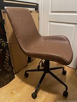 Front side angle view of the brown leather office chair showing its contoured seat and stitched edges.