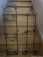 Front view of the two iron wall-mounted plate racks showing decorative scroll designs and plate holders.