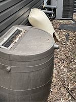 View of whole rain barrel with screen on top and outlet spigot visible.
