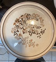 Top view of Shannon Aran Stone decorative plate with floral design and double brown rim lines.