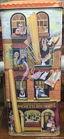 Front side of the rectangular metallic spaghetti tin showing the multi-story building facade illustration with people and spaghetti strands.