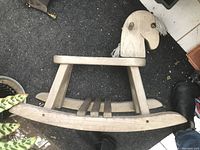 Wooden rocking horse shown from side with visible curved rockers, seat slats, and horse head with yarn mane