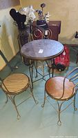 Photo of round wooden bistro table with wrought iron base and two of the matching chairs.