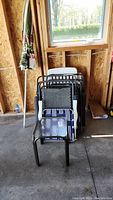 Full lot view showing stacked chairs and end table, umbrella leaning against wall in a garage setting.