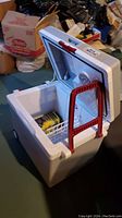 Electric cooler open showing interior with a small basket and inner compartment.