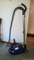 Miele canister vacuum body with hose and telescopic wand upright on carpet