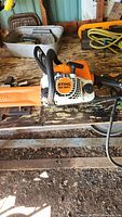 Front view of Stihl MS 180C chainsaw showing model label and chain bar cover on wooden workbench.