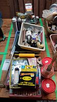 Overview of assorted tools and hardware, including staple gun, brushes, spout pourer and staples box on a table.