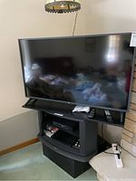 Front view of the LG 50 inch TV with Sony DVD player below on TV stand, includes remotes.