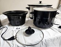 Three slow cookers including Euro-Pro large oval, small Euro-Pro, and Crock-Pot 2-quart model with lids and removable crocks placed on table
