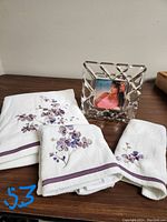 Photo showing white towel set including bath towel, hand towel, and washcloth with lavender flower embroidery next to a Mikasa crystal picture frame containing a 4x4 inch photo.