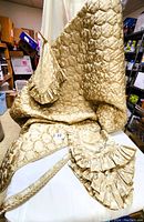 Full view of gold quilted comforter with braid cord trim and matching pillows and shams displayed on table