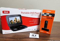 Box of RCA Portable DVD Player and Amazon Fire TV Stick 4K showing front packaging of both items