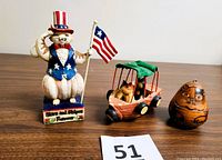 Full view of three cat-themed folk art items on display: Jim Shore figurine, calico cats in boat carving, and carved cat gourd ornament.