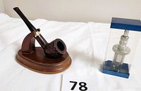 Photo showing the Dr. Grabow rustic textured pipe on a wooden stand next to the Kaywoodie pipe reamer in its display case.