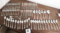 Full overview of entire flatware set laid out on table showing all pieces included in this lot.