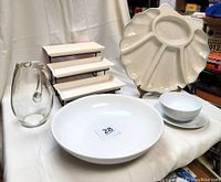 Wide view of lot showing all main items including shell platter, three-tier stand, large bowl, Ikea plate and bowl, and glass pitcher