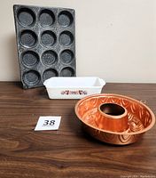 Overall shot of the three items showing the loaf dish, muffin pan, and copper mold on a wood surface.