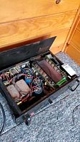 Power amplifier with lid open showing internal wiring and components including capacitors and coils.