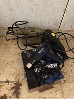 Photo showing the Mastercraft heat tool on its box, next to a beige rectangular base electric sander, both with cords visible.