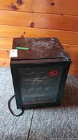 Front view of Igloo wine cooler showing glass door and metal frame with power cord alongside