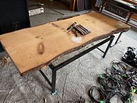Top view of the live edge wood table top showing the natural grain, knots, and live edges with some tools resting on the surface.