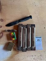 Four M. Hohner harmonicas with two knives and two lighters on a wooden surface.