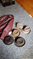 Photo showing burgundy leather jacket and five various hats including plaid and fedora styles
