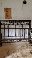 Photo of the metal bed frame showing decorative scrollwork and floral patterns on the frame.