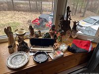 Photo of the entire lot showing figurines, ironstone plate, glasses, and other miscellaneous items on a wooden bench by a window.