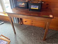 Full view of oak veneer rectangular table showing the top, legs, and surrounding area with visible surface marks