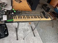 Full view of Roland XP-10 synthesizer keyboard on stand with power adapter and cables, showing overall condition and layout.