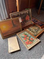 Six framed prints resting on carpet, showing floral, sailboat, barn, and wildlife themes