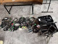 Photo showing multiple cables, charger, tripod, and other accessories laid out on carpet.