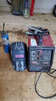Welder unit, welding helmet, and fuel cylinder torch arranged on wooden floor