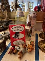 Front view showing Johnny Carson book, two cocktail shakers, and bottle stoppers on table with other decorative items