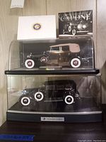 Two Franklin Mint model cars displayed in separate clear cases with a plaque showing Franklin Mint brand; includes the 1941 Lincoln Continental and Al Capone armored Cadillac replicas.