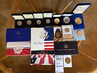 Overview of coin collection including multiple boxed silver coins, medallions, certificates and booklets