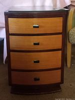 Front view of the vintage Johnson Handley chest showing four drawers with light wood fronts and dark frame, metal handles, and glass top.