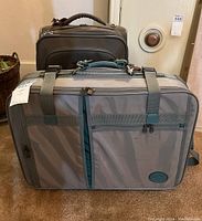 Front angled view of the brown Ricardo rolling suitcase behind the gray Boyt duffle-style bag showing bag size and condition.